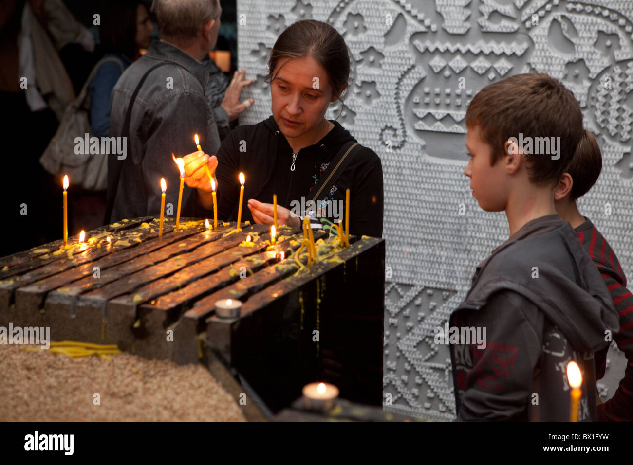 A mother and her children lighting a candle for the victims of the 1932-1933 famine at the Holodomor Museum in Kiev, Ukraine Stock Photo