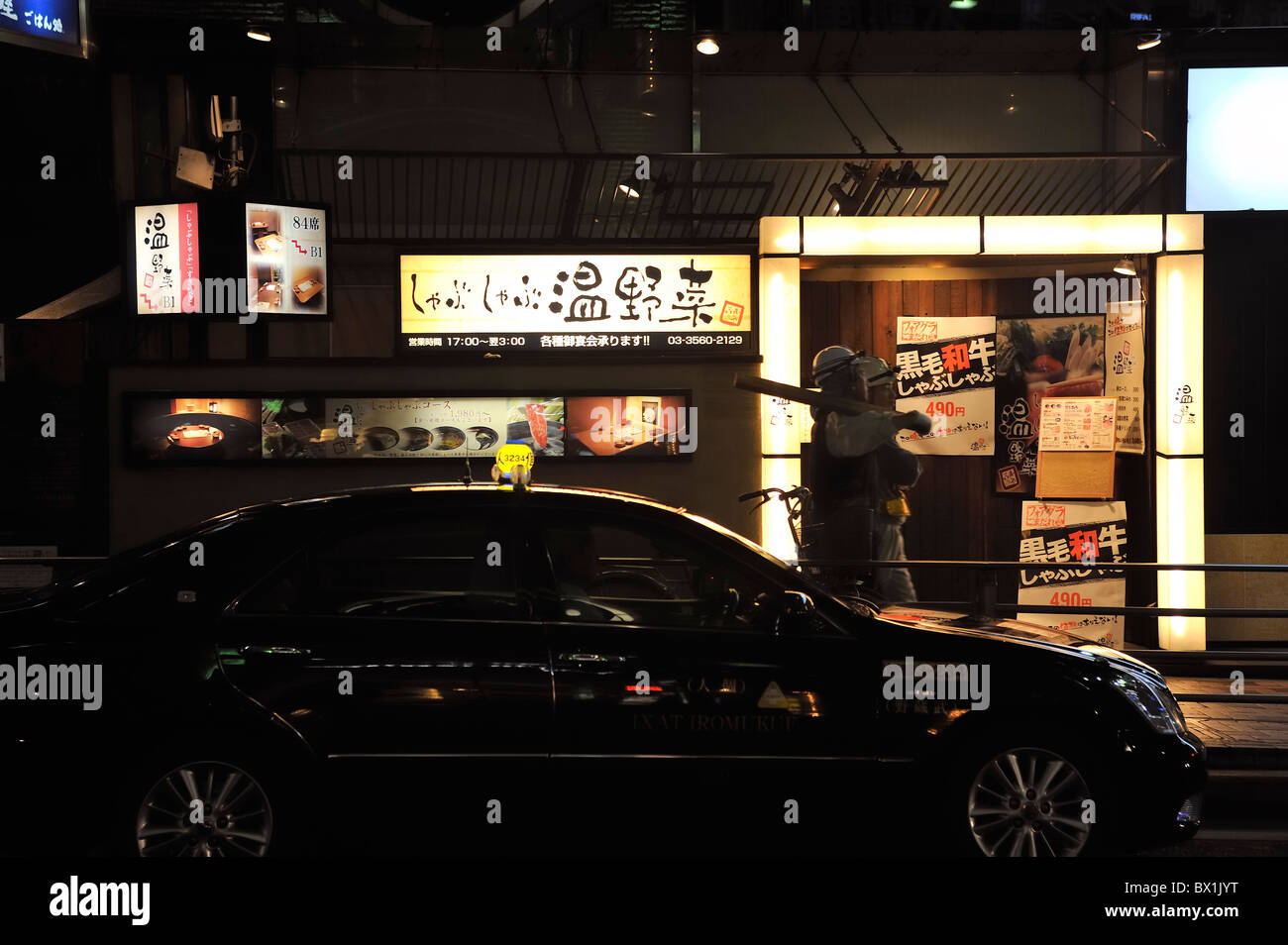 Two workers passing a restaurant at night, Tokyo, Japan Stock Photo