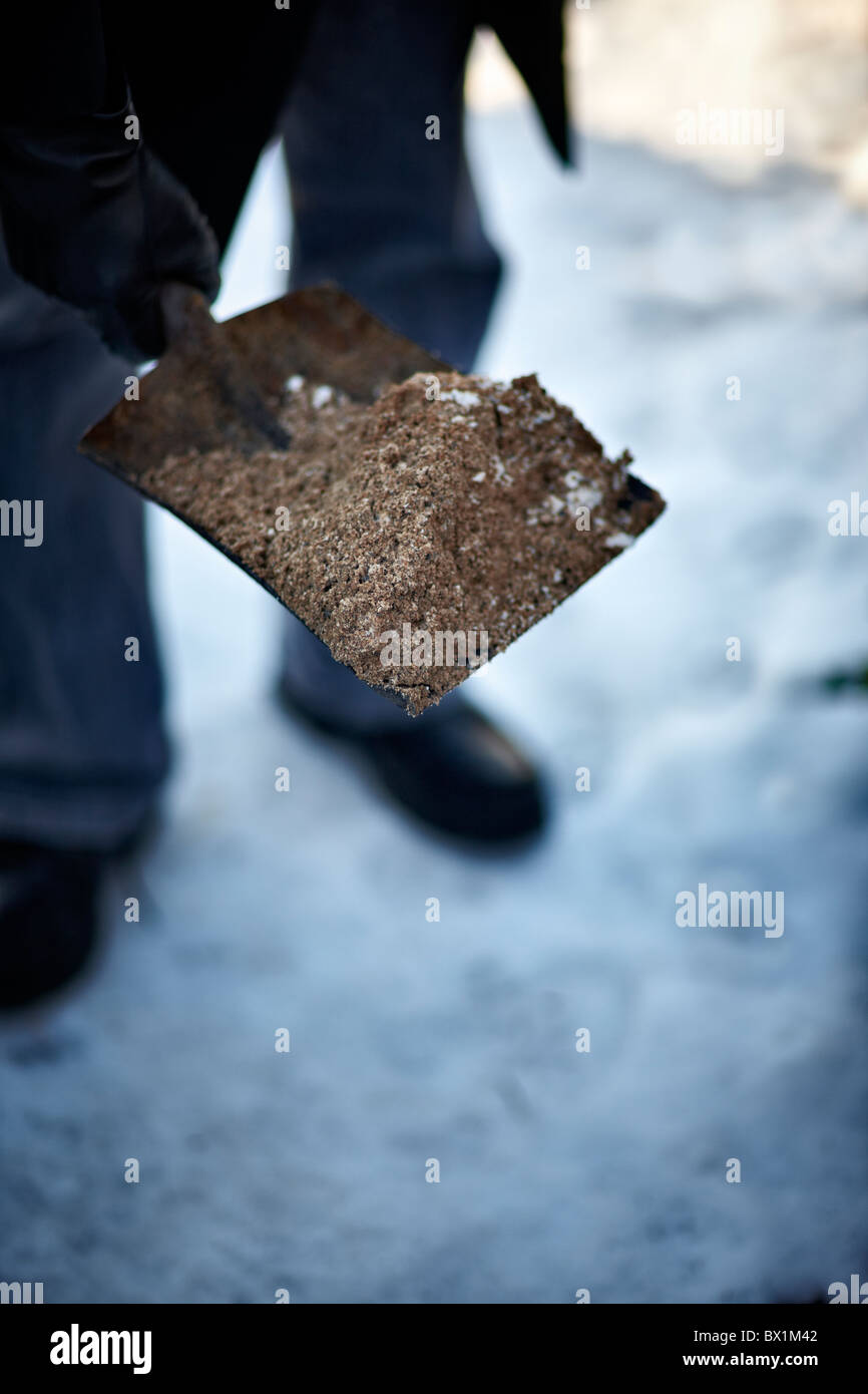 Older person using grit on an icy path Stock Photo