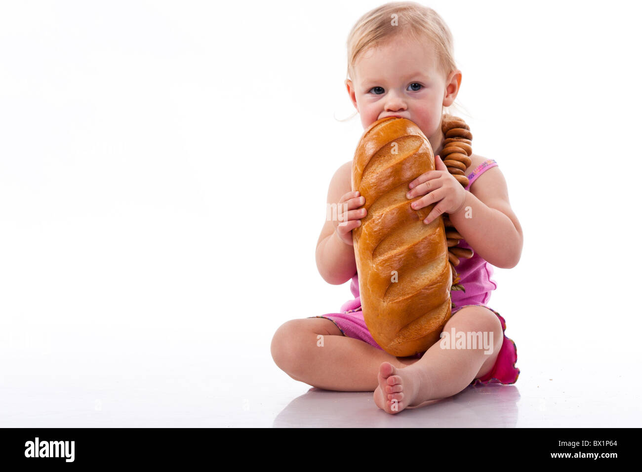 Baby eating a loaf of bread in roll beads isolated on white Stock Photo