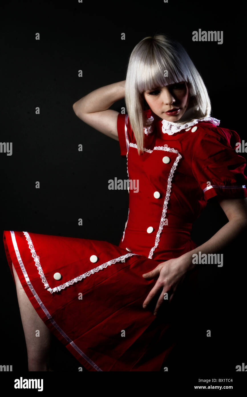 Fashion portrait of a young blonde model wearing a red gothic lolita dress. Stock Photo