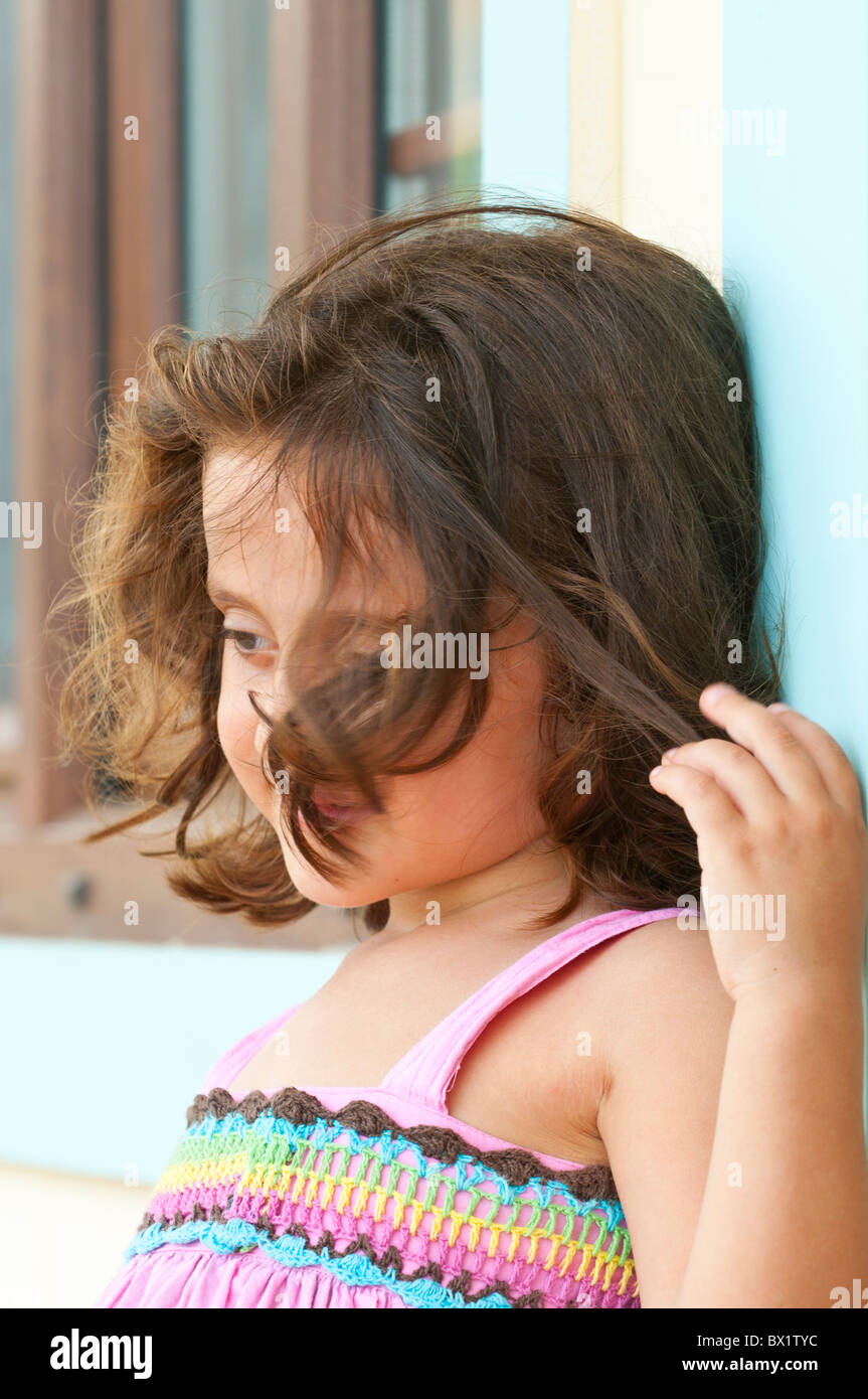Little girl playing with her hair while standing outdoors Stock Photo ...