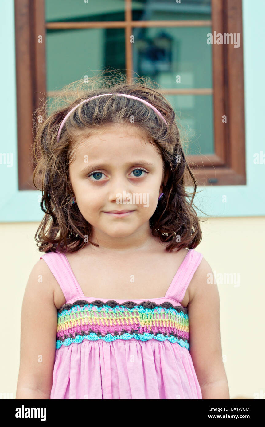 Beautiful little girl standing outside her house in pink dress Stock Photo
