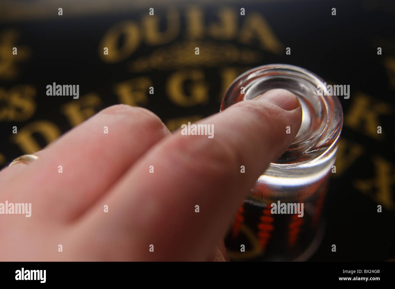 Finger on top of a glass on a Ouija board Stock Photo