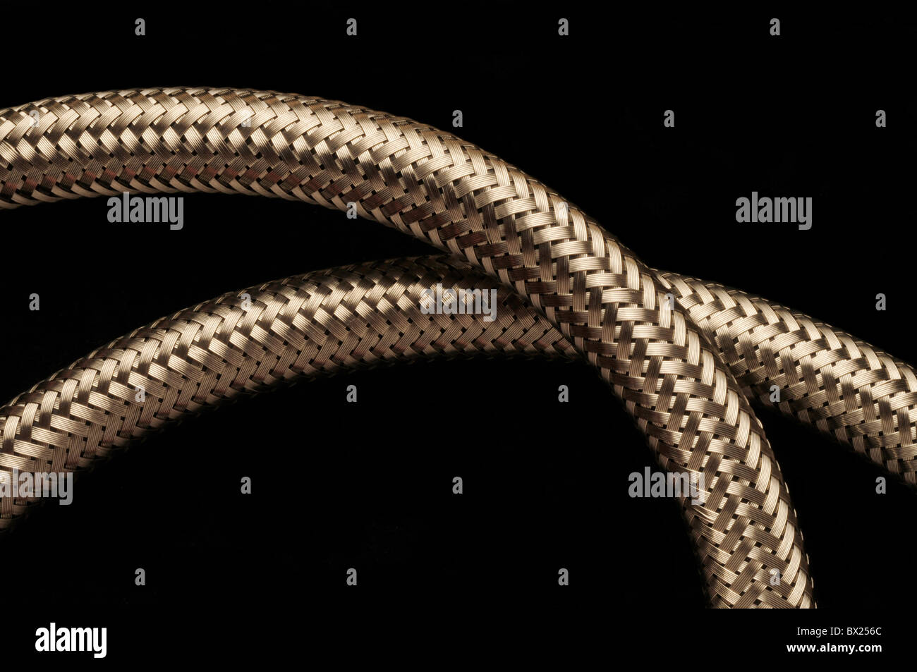 Two flexible metallic stainless steel piping tubes against black background Stock Photo
