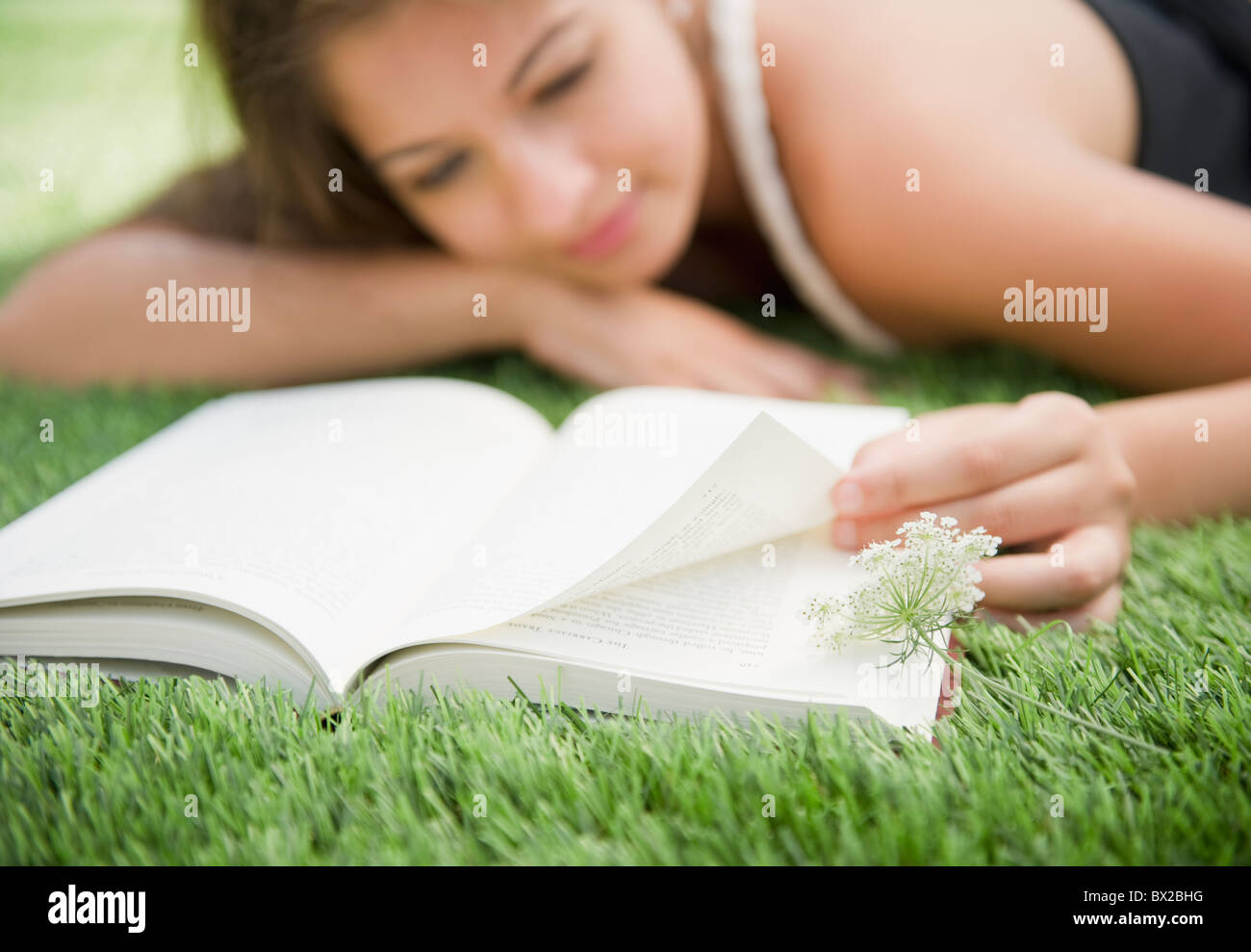 Indian woman laying in grass reading book Stock Photo