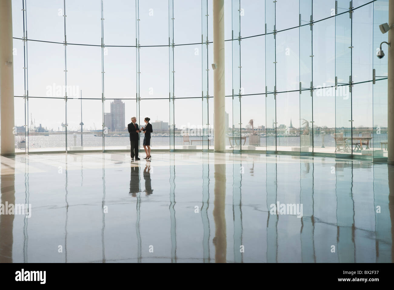 Business people talking in office lobby with glass wall Stock Photo