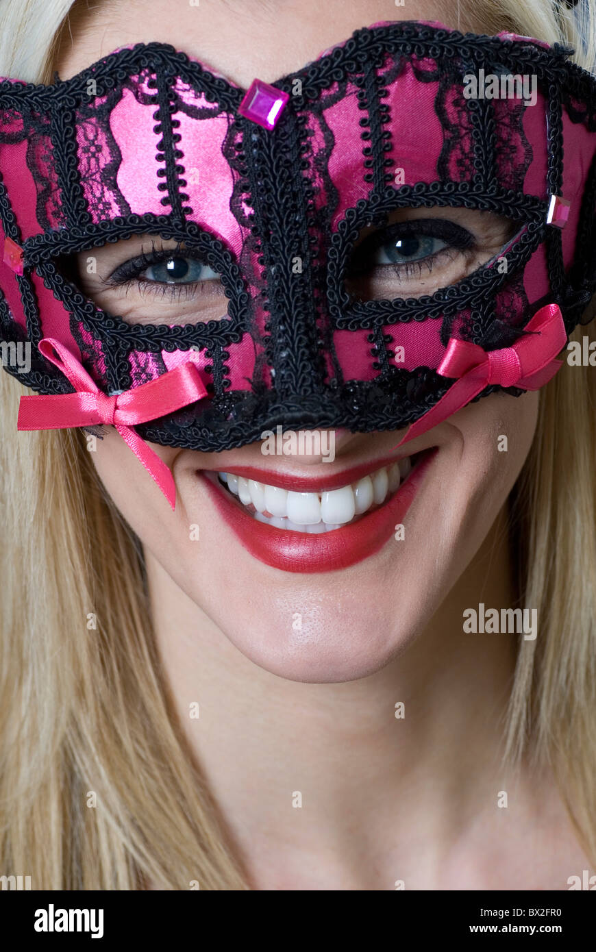 Young woman in pink party mask Stock Photo