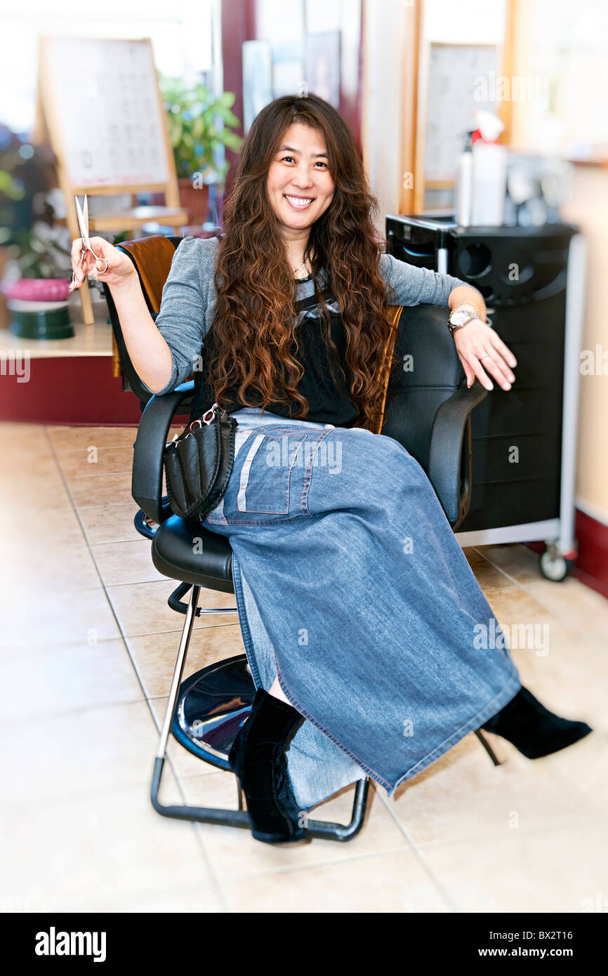 Hairstylist sitting in a chair in her hair salon Stock Photo