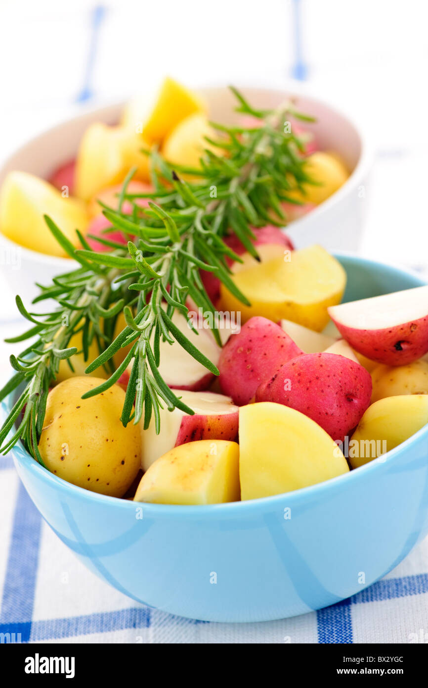 Bowl of cut raw small potatoes with skins and herbs ready for roasting