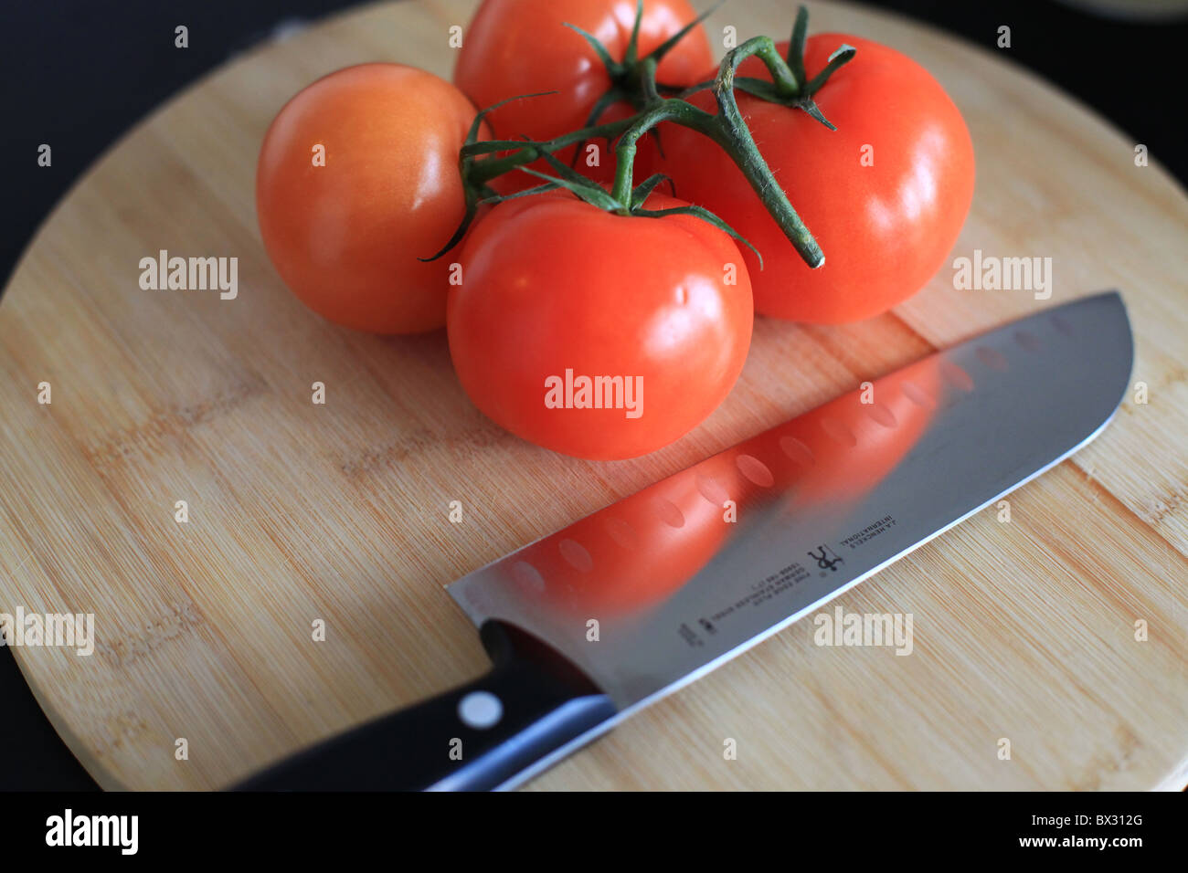 Red tomatoes and a steel knife on cutting board Stock Photo - Alamy