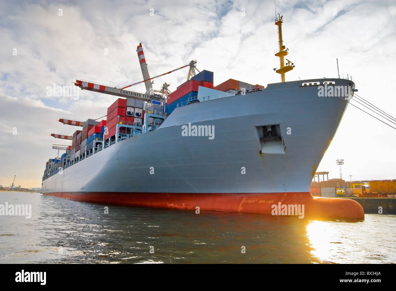 Cargo freight ship with stacked container at harbour terminal Stock Photo