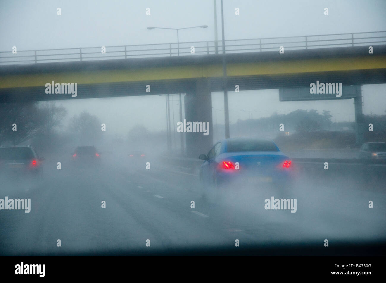 Drivers view through a car windscreen showing difficult driving conditions, and poor visibility (spray and fog) on a motorway. Stock Photo