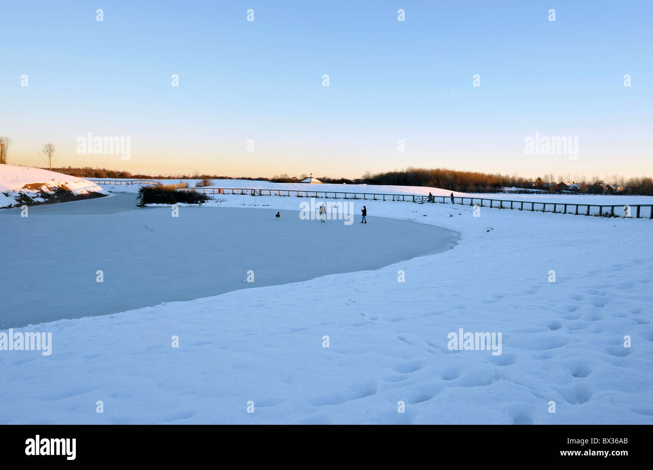 Ignoring KEEP OFF THIN ICE signs. Two people risk walking out onto the ice IN A PUBLIC PARK. Stock Photo