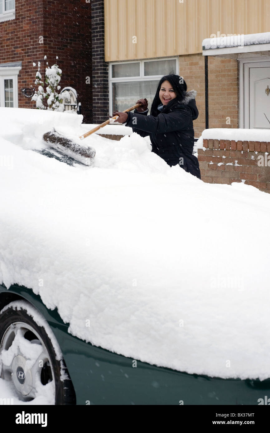 young woman clearing deep snow off a car with a broom Stock Photo Alamy