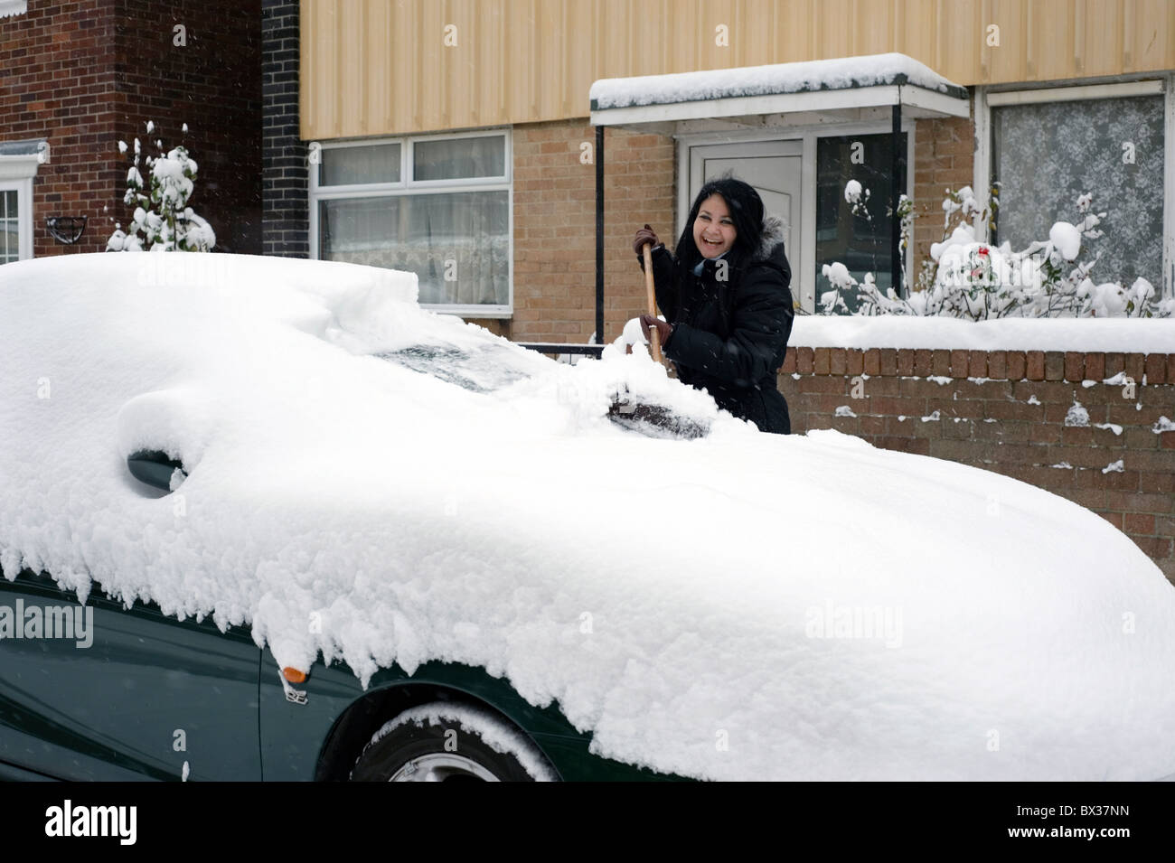 young woman clearing deep snow off a car with a broom Stock Photo Alamy