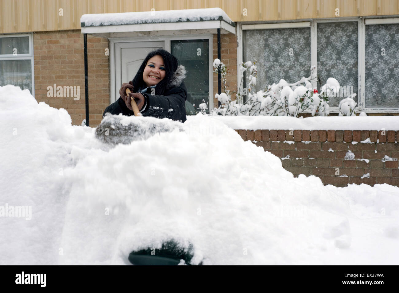 young woman clearing deep snow off a car with a broom Stock Photo Alamy