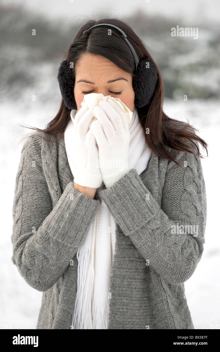 Woman blowing runny nose on cold winter day Stock Photo