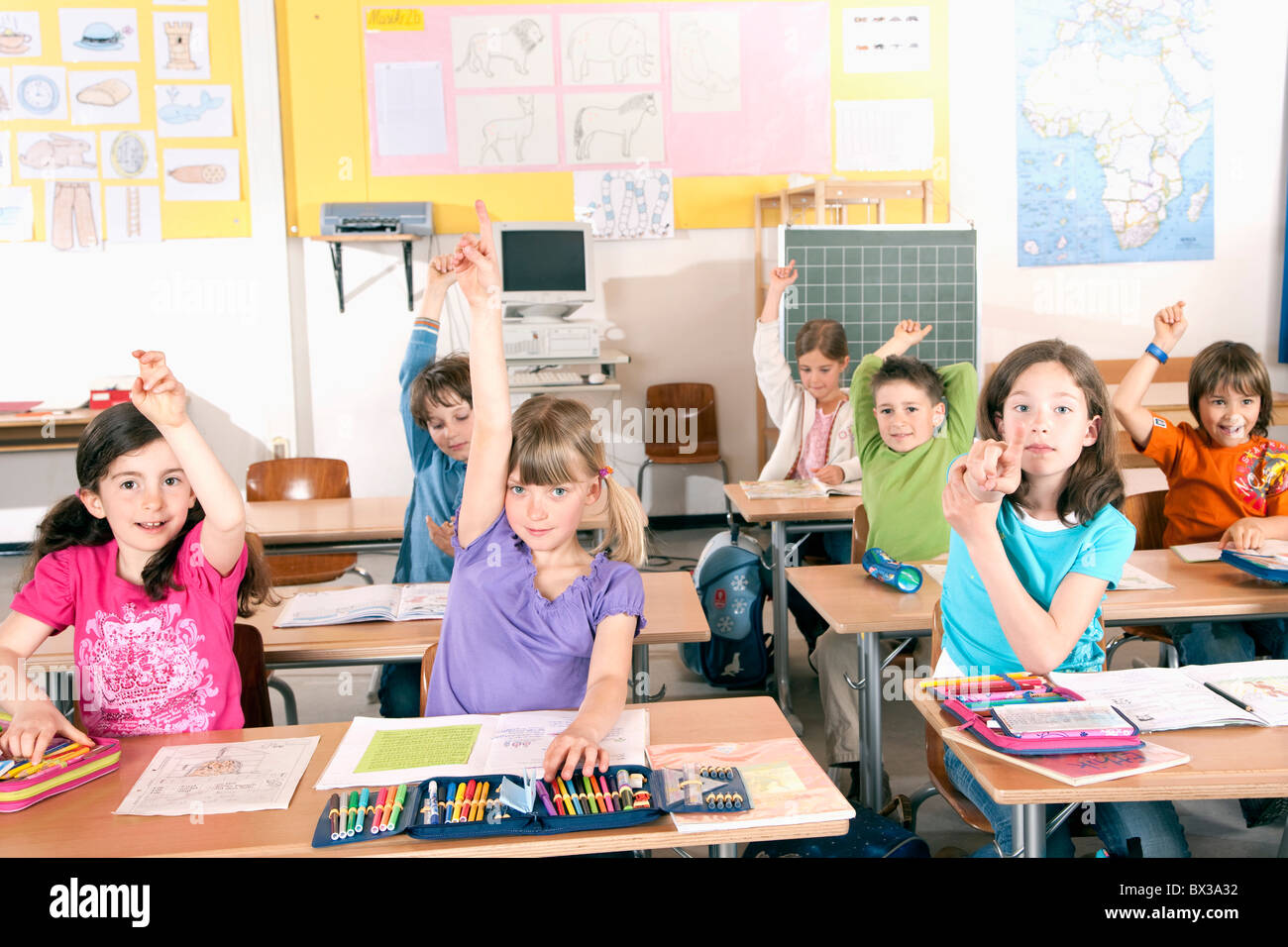 group of pupils raising their fingers in classroom Stock Photo