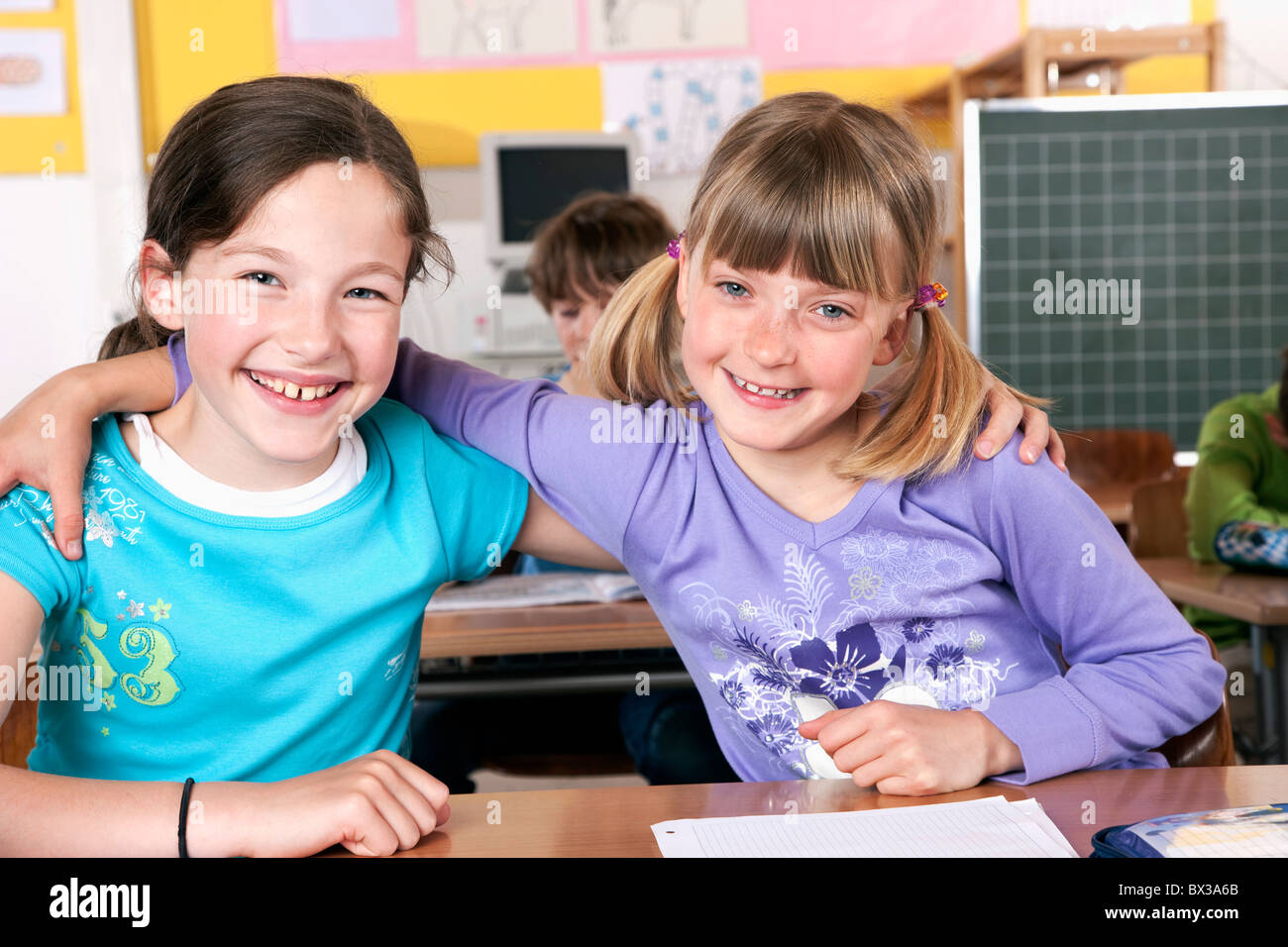 portrait of two young girls in classroom embracing Stock Photo - Alamy