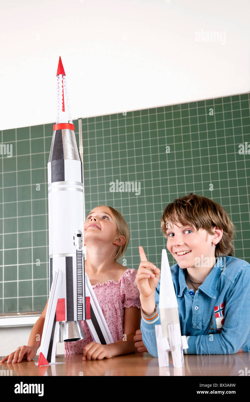 two pupils in classroom with model of rocket Stock Photo