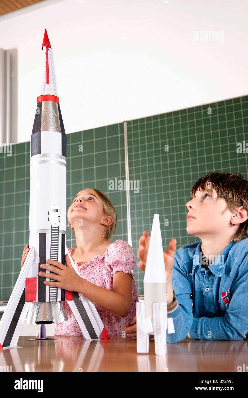 two pupils in classroom with model of rocket Stock Photo