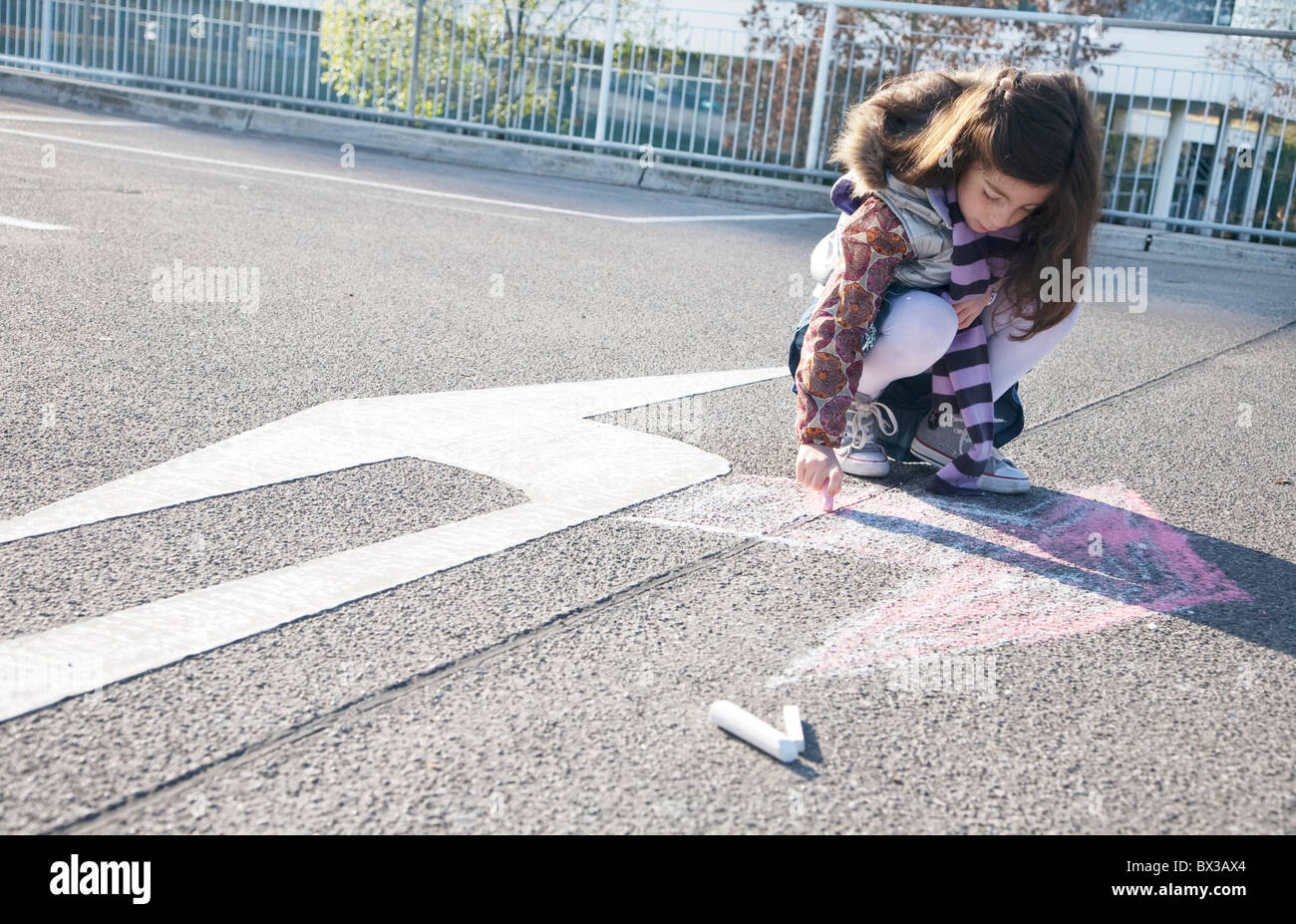 young girl drawing arrow in opposite direction of road sign Stock Photo