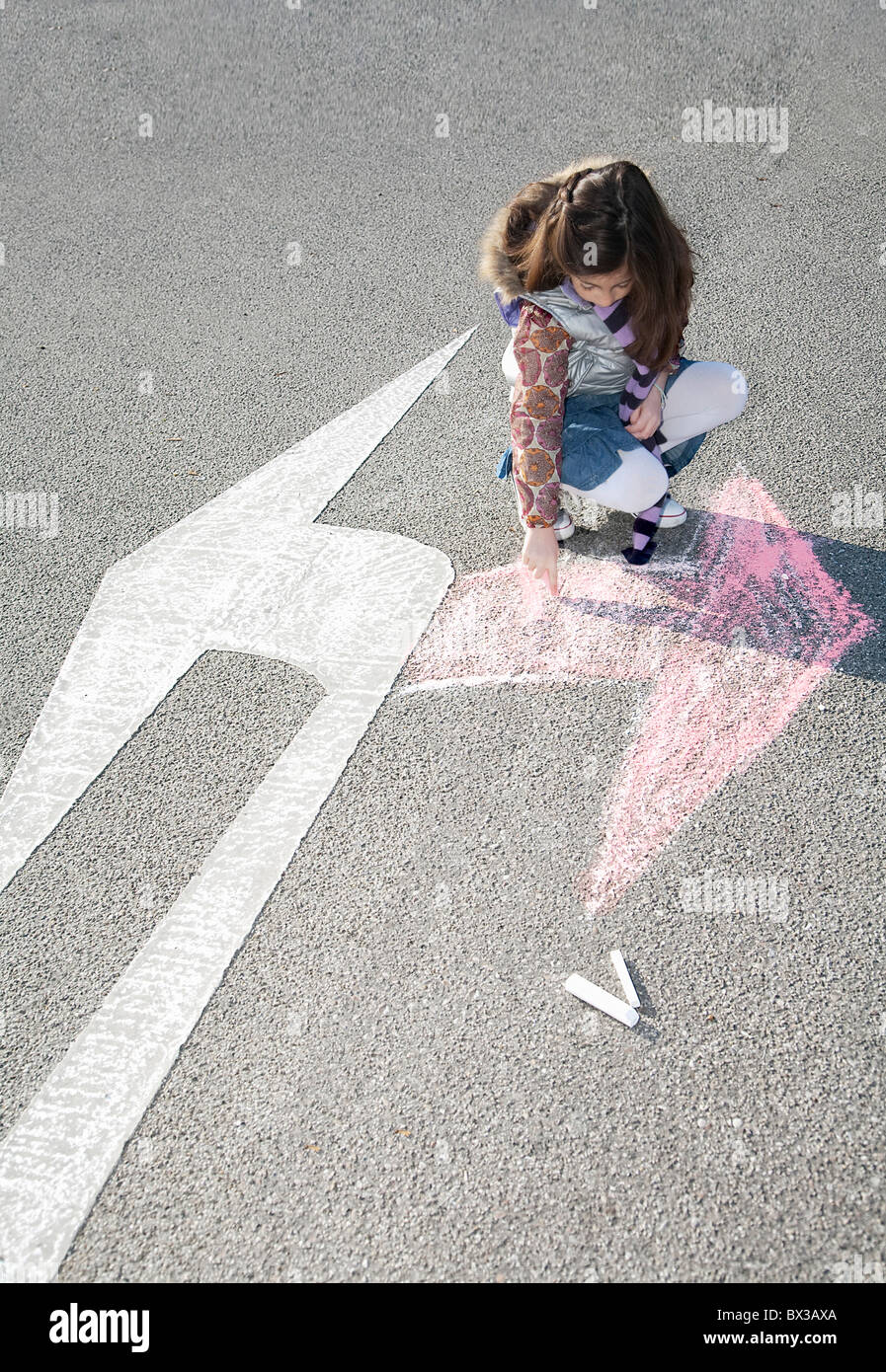 young girl drawing arrow in opposite direction of road sign Stock Photo