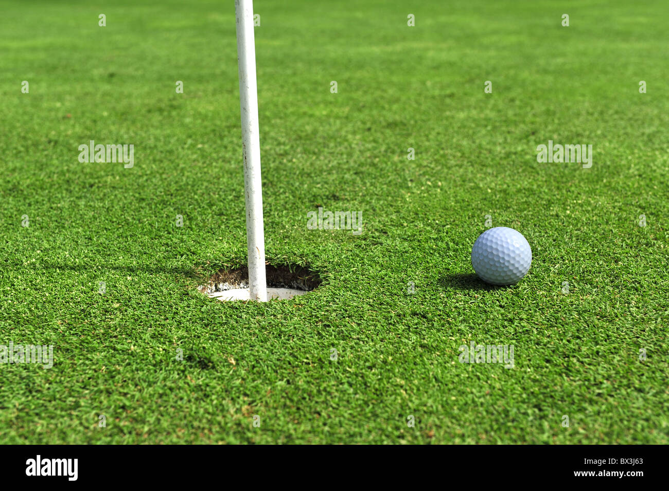 A golf ball has stopped close to the hole ready for an easy tap in. Stock Photo