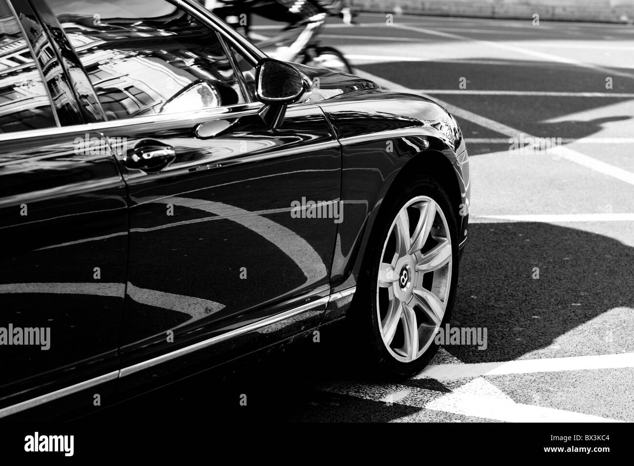 Black and white image of a Bentley luxury car driving down the street of London Stock Photo