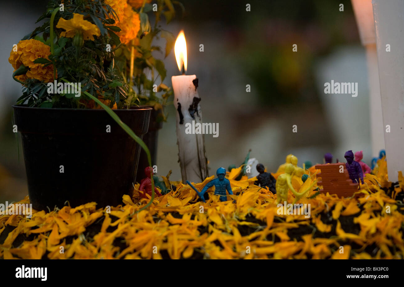 Plastic toy soldiers decorate a tomb adorned with yellow marigold flowers, known as Zempasuchitl, in Xochimilco, Mexico City. Stock Photo