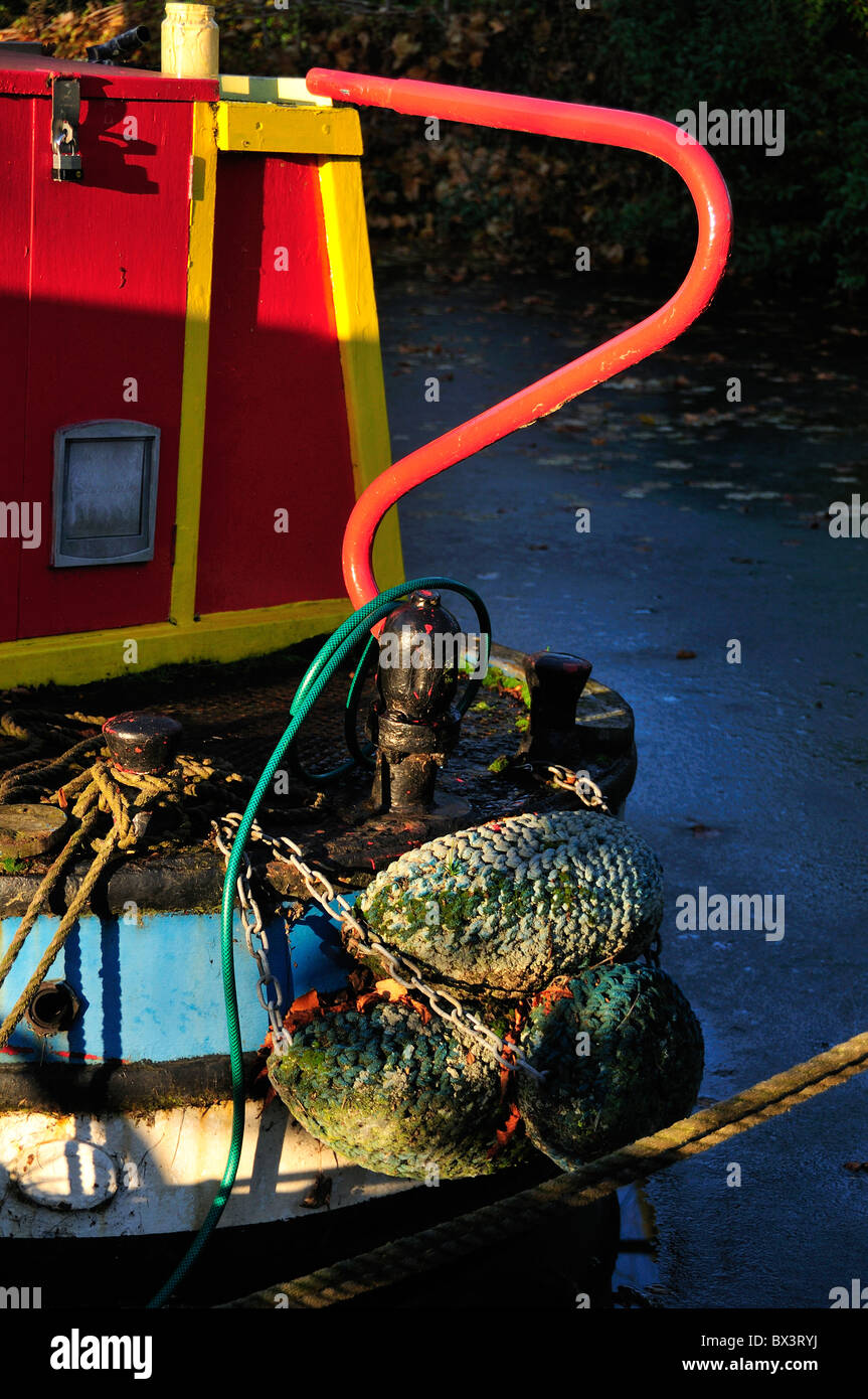 Stern showing tiller and fenders of old narrow boat with frozen water on a winter's day on the