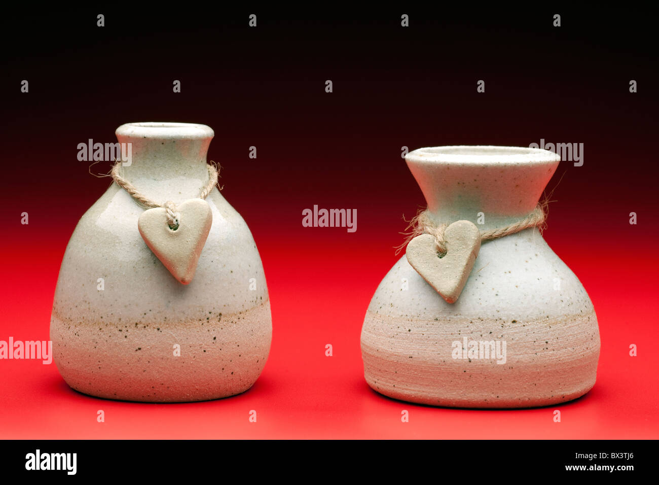 Two stone hearts on string wrapped around two ceramic pots Stock Photo