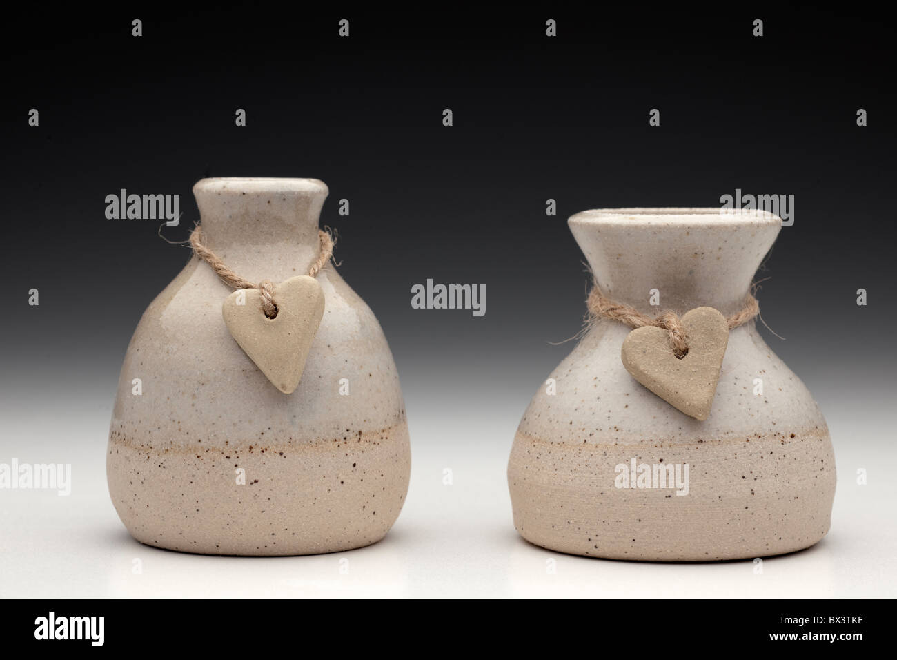Two stone hearts on string wrapped around two ceramic pots Stock Photo