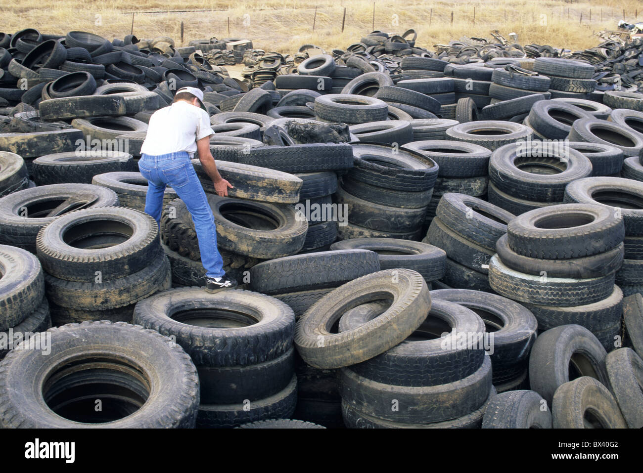 Worker piling discarded old tires for recycling, United States Stock Photo