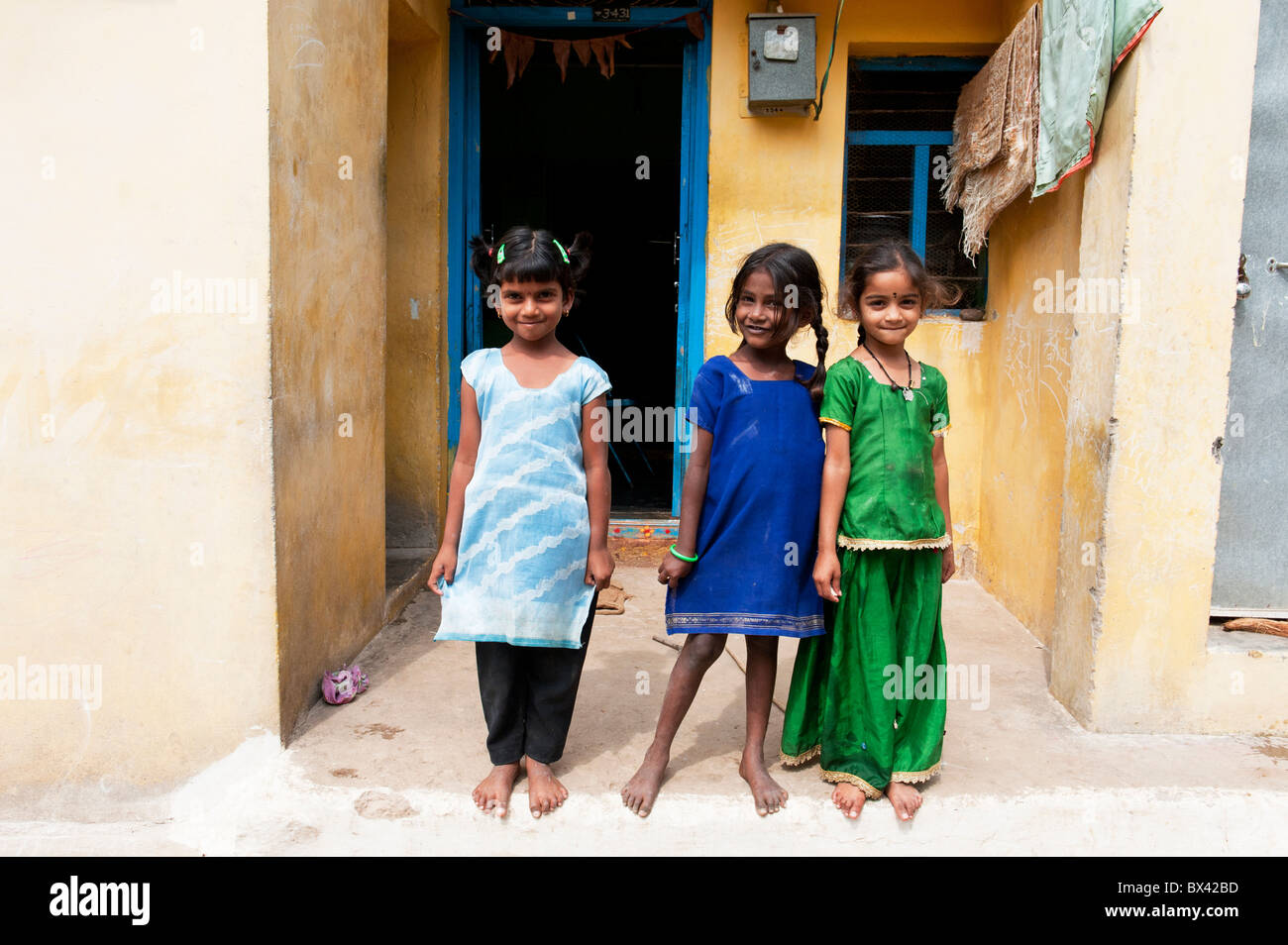 Smiling happy Indian village girls standing in front of their house.  Andhra Pradesh, India Stock Photo