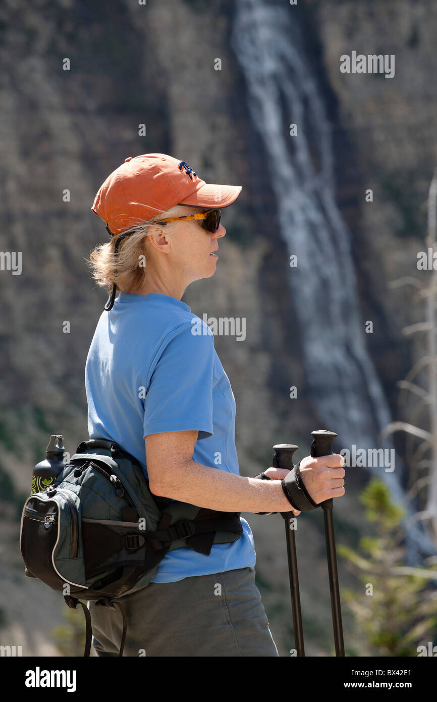 Female Hiker With A Waterfall In The Background; Waterton, Alberta, Canada Stock Photo