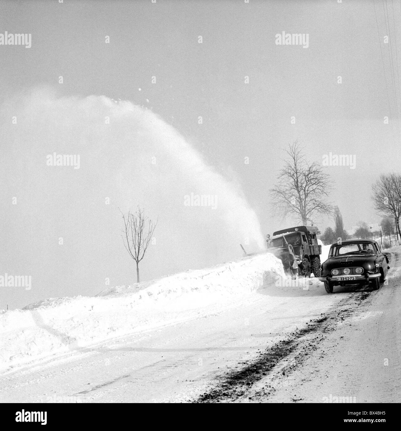 Tatra 603 automobile passes snow plow dicarding snow on slippery road. Vrchlabi Czechoslovakia 1963. (CTK Photo / Erik Strazab) Stock Photo