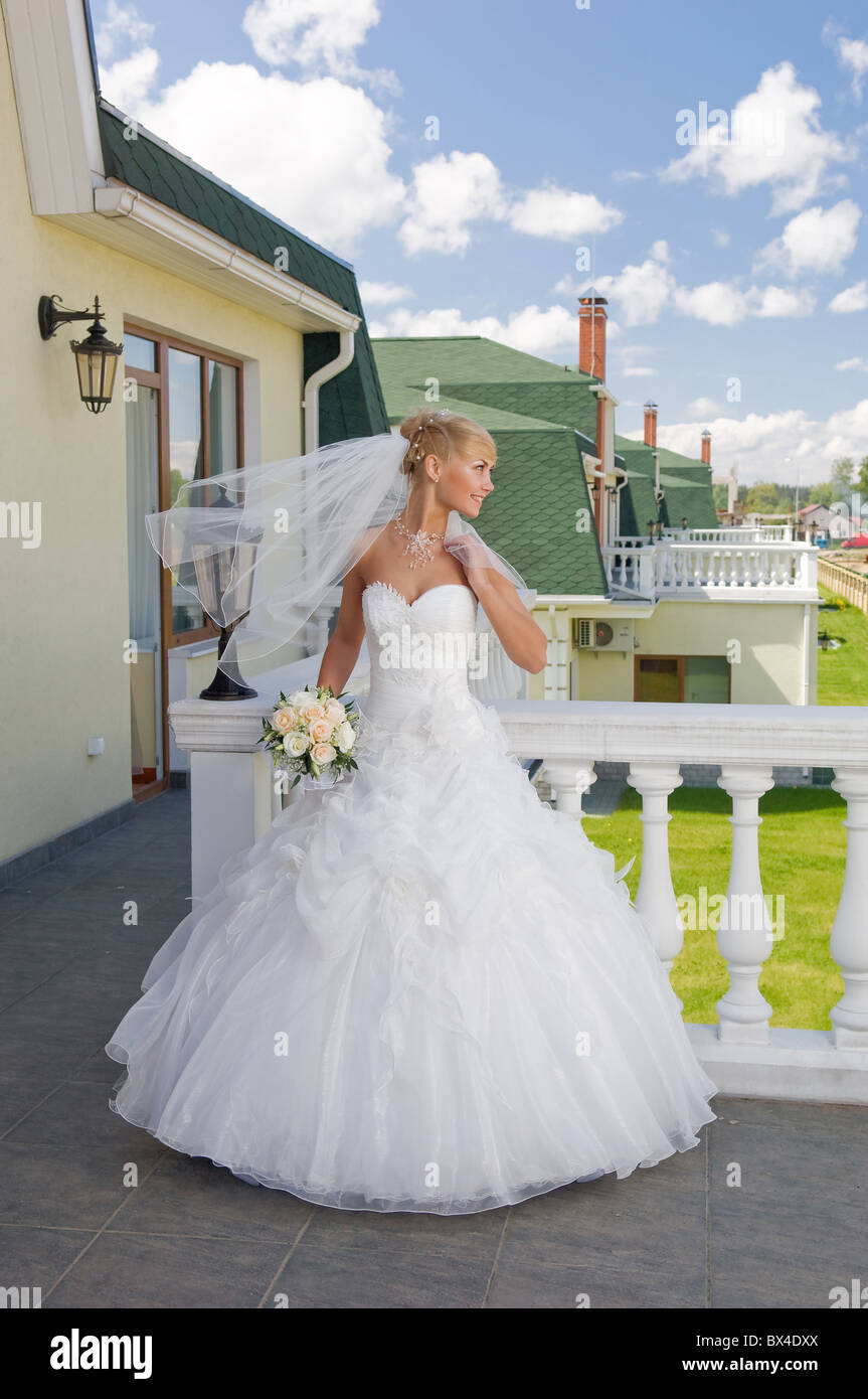 Beautiful blonde bride with bunch of roses on the balcony Stock Photo ...
