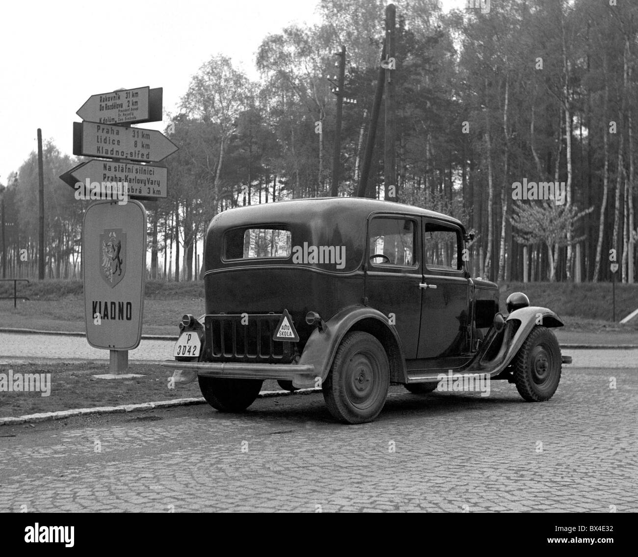 Kladno - Czechoslovakia, 1950. Car driver checks direction signs at intersection. CTK Vintage Photo Stock Photo