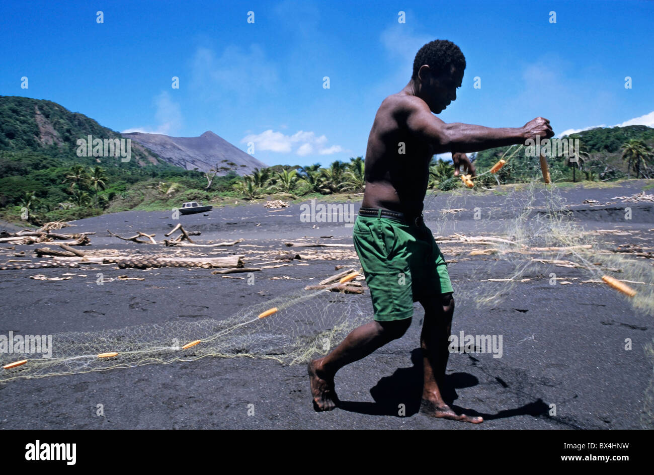 Vanuatu - Fisherman on a black sand beach preparing his nets, Sulphur Bay Village, Tanna Island, Vanuatu. Stock Photo