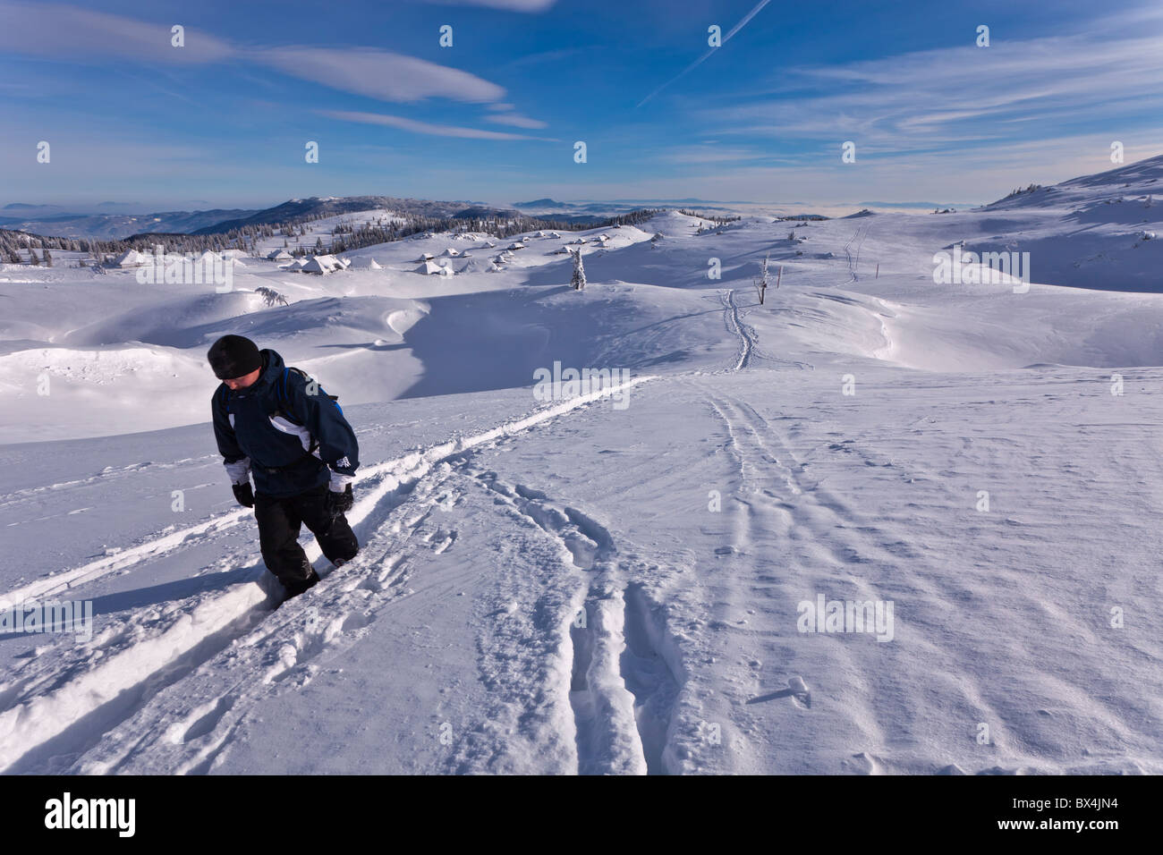A man follows a path in the deep snow of Velika Planina, Slovenia. Stock Photo