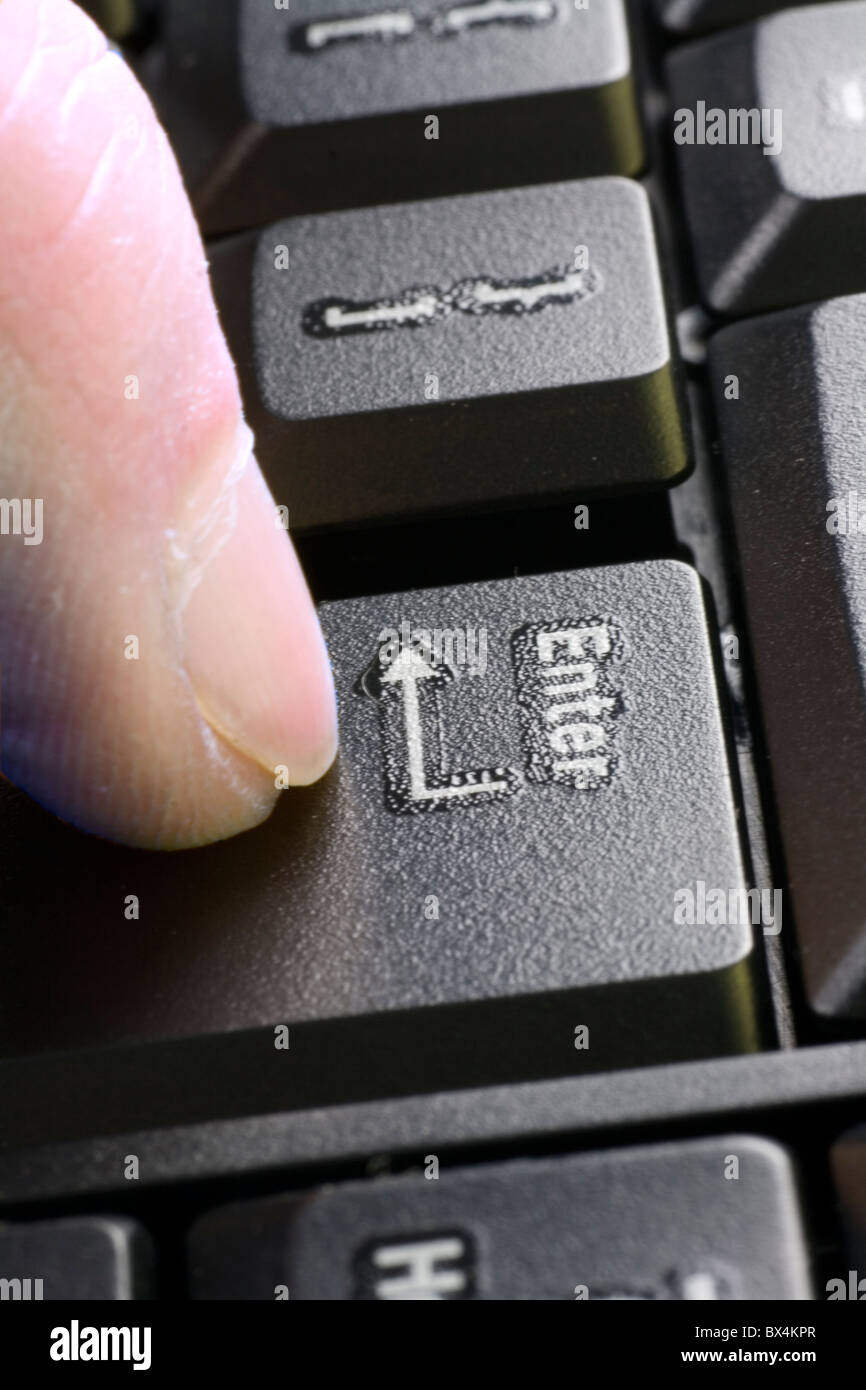 A finger on the Enter key. Stock Photo
