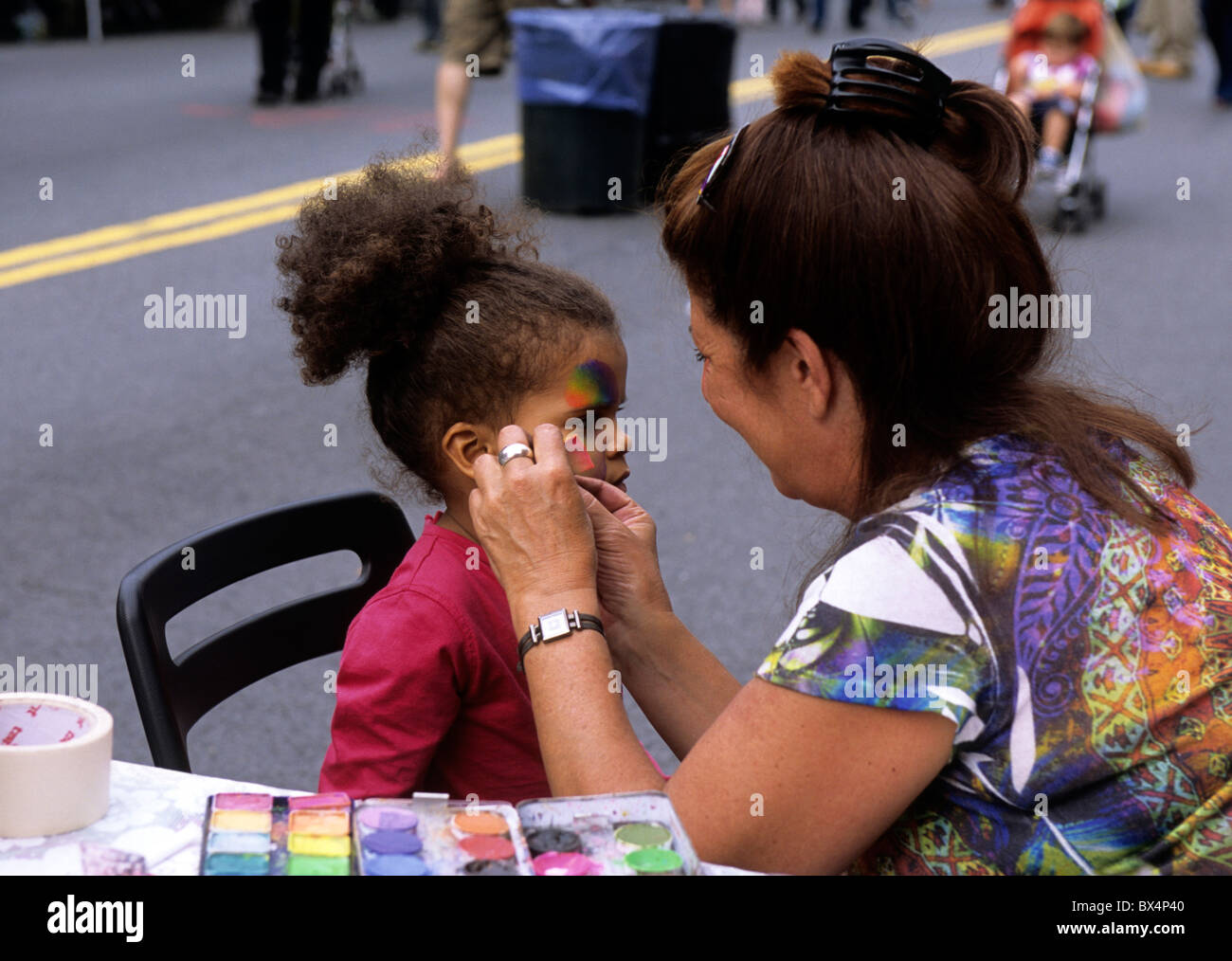 An artist face painting a pretty young child at a New York street fair, or street festival, in Brooklyn, New York City. Stock Photo