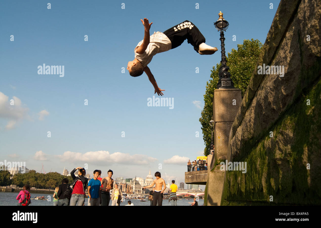 A Parkour Free runner backflips off a ledge on the South side of the river Thames in London. Stock Photo
