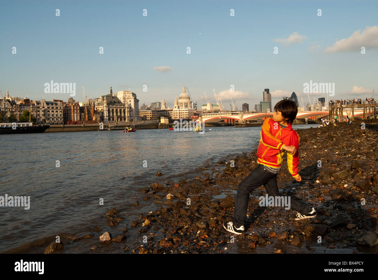 Young child playing on the shores of the river Thames in central London. Stock Photo