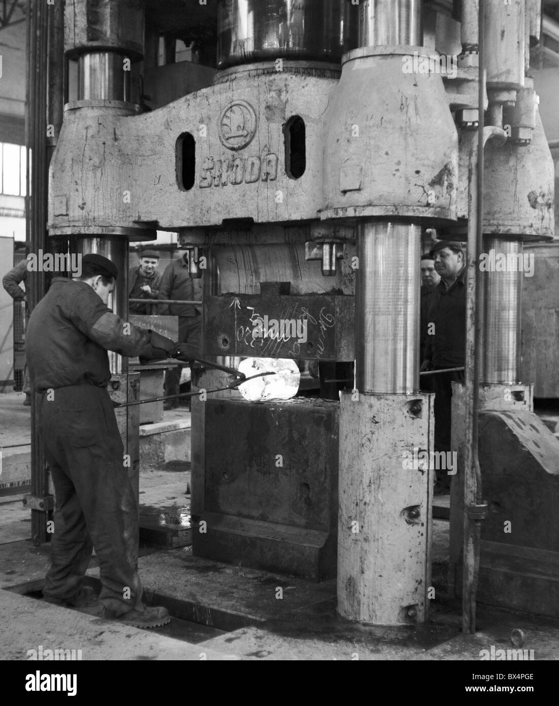 Steel worker positions hot steel piece into the presser. Hradec Kralove, Czechoslovakia 1963. (CTK Photo / Jaroslav Sladek) Stock Photo