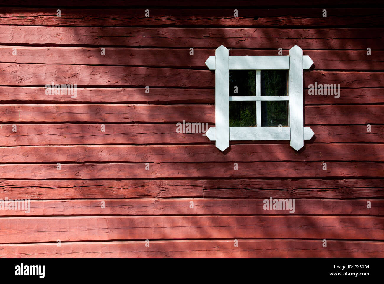 Red ochre painted old log cabin wall and a small window , Finland Stock Photo