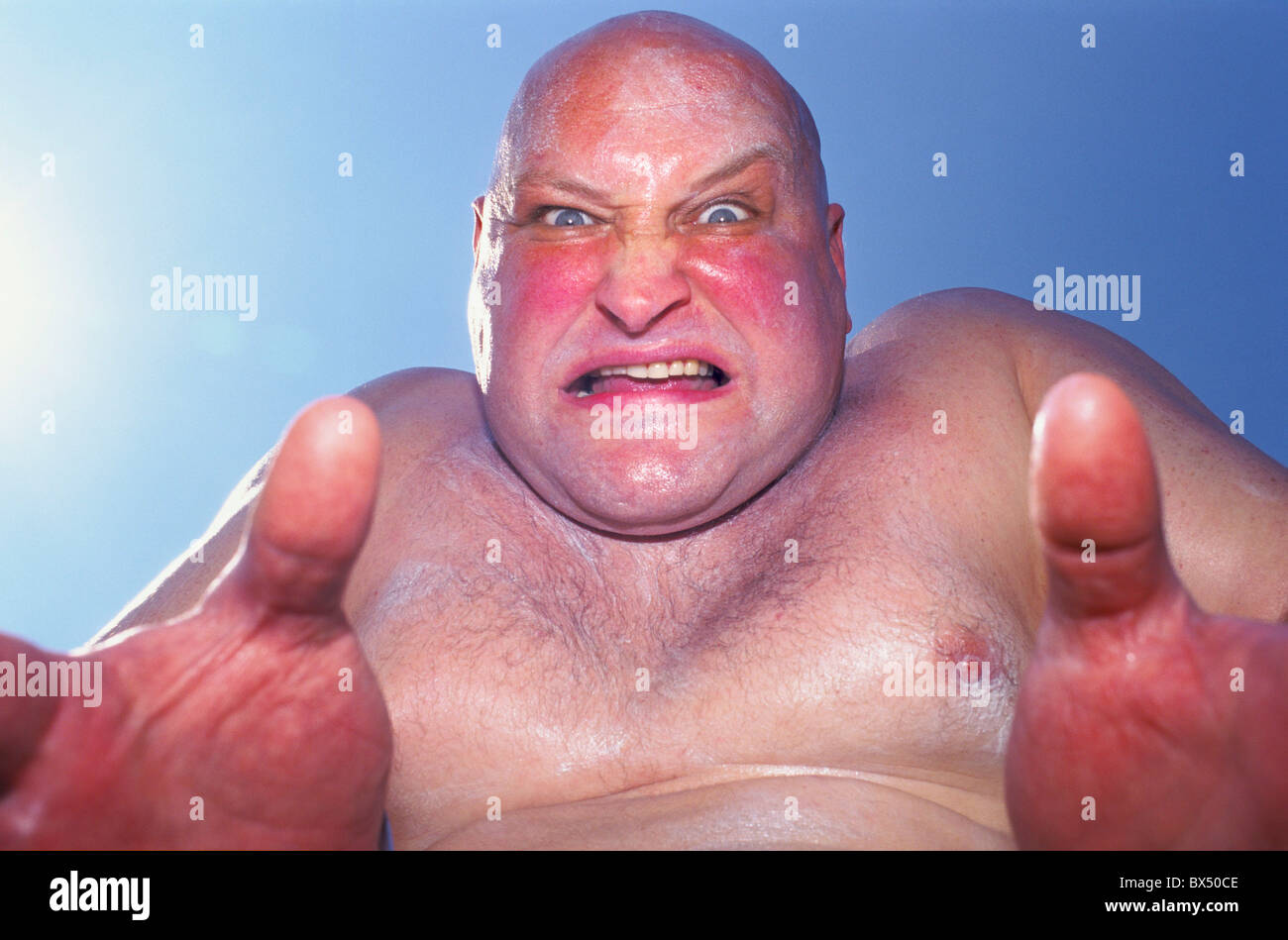 An obese, sweaty bald man poses for a picture at the Urban Games. Stock Photo