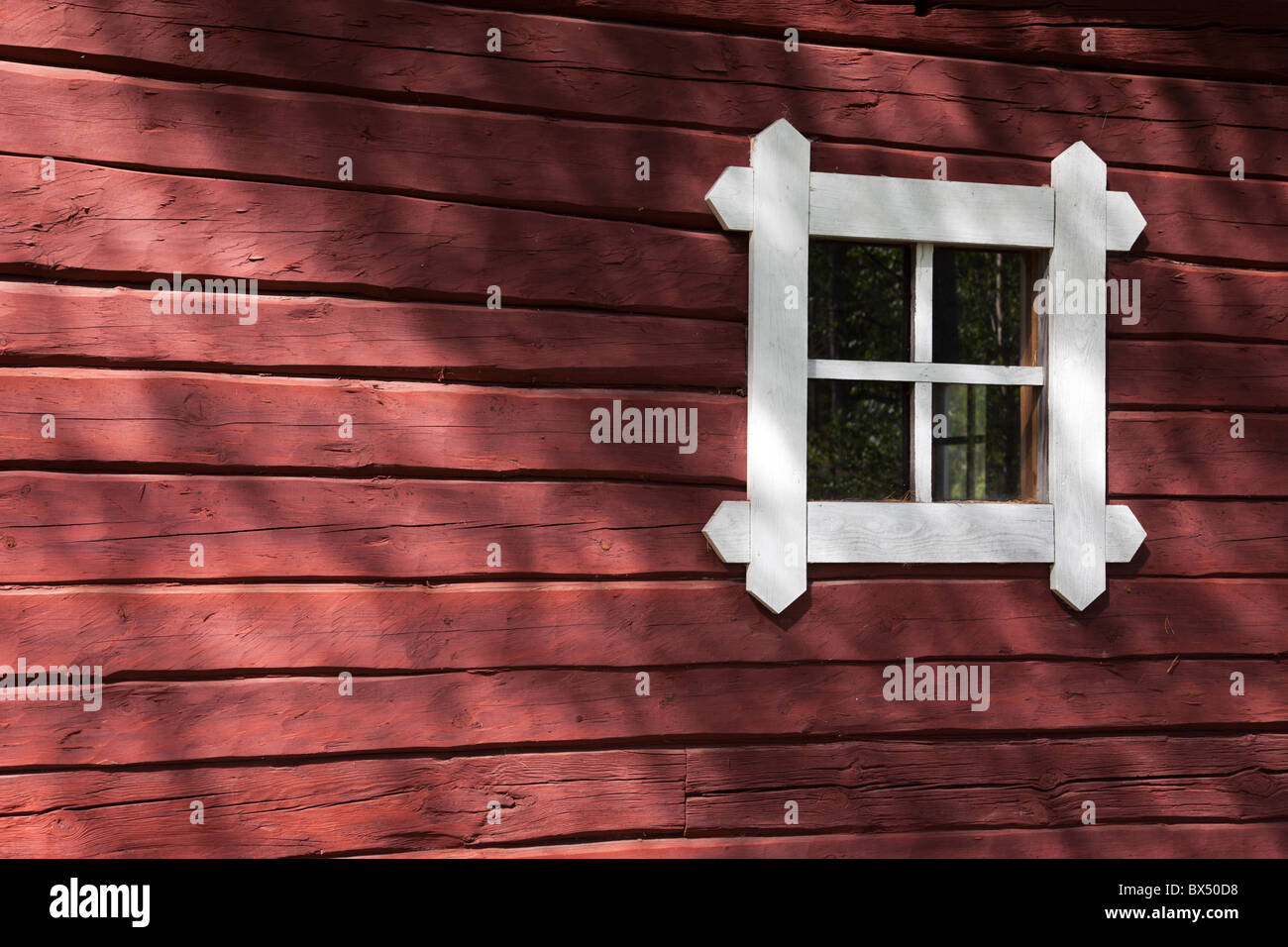Red ochre painted old log cabin wall and a small window , Finland Stock Photo